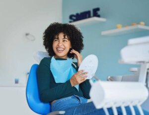 patient holding up mirror and smiling at dentist after fillings
